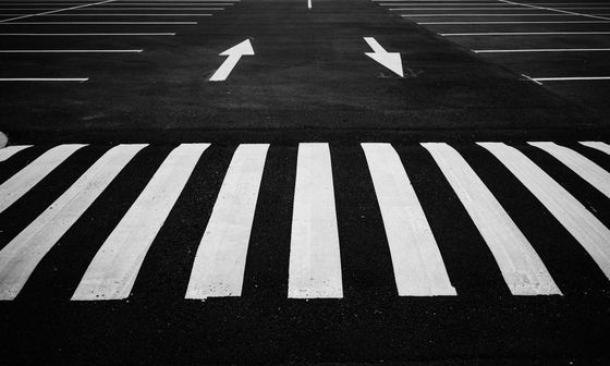 A black and white photo of a crosswalk with arrows pointing in opposite directions