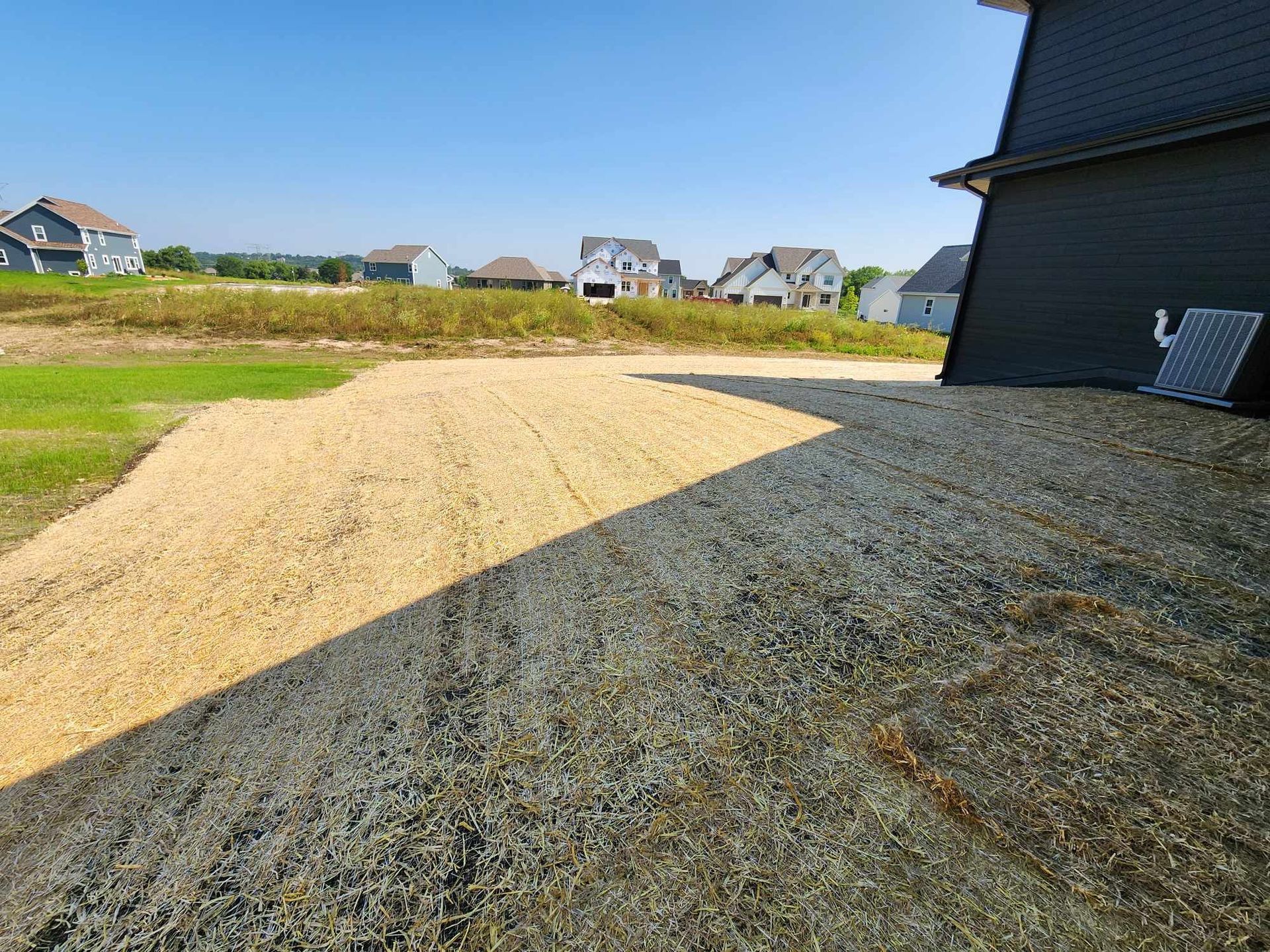 Gravel driveway and yard next to a house under construction; other houses visible in the distance.