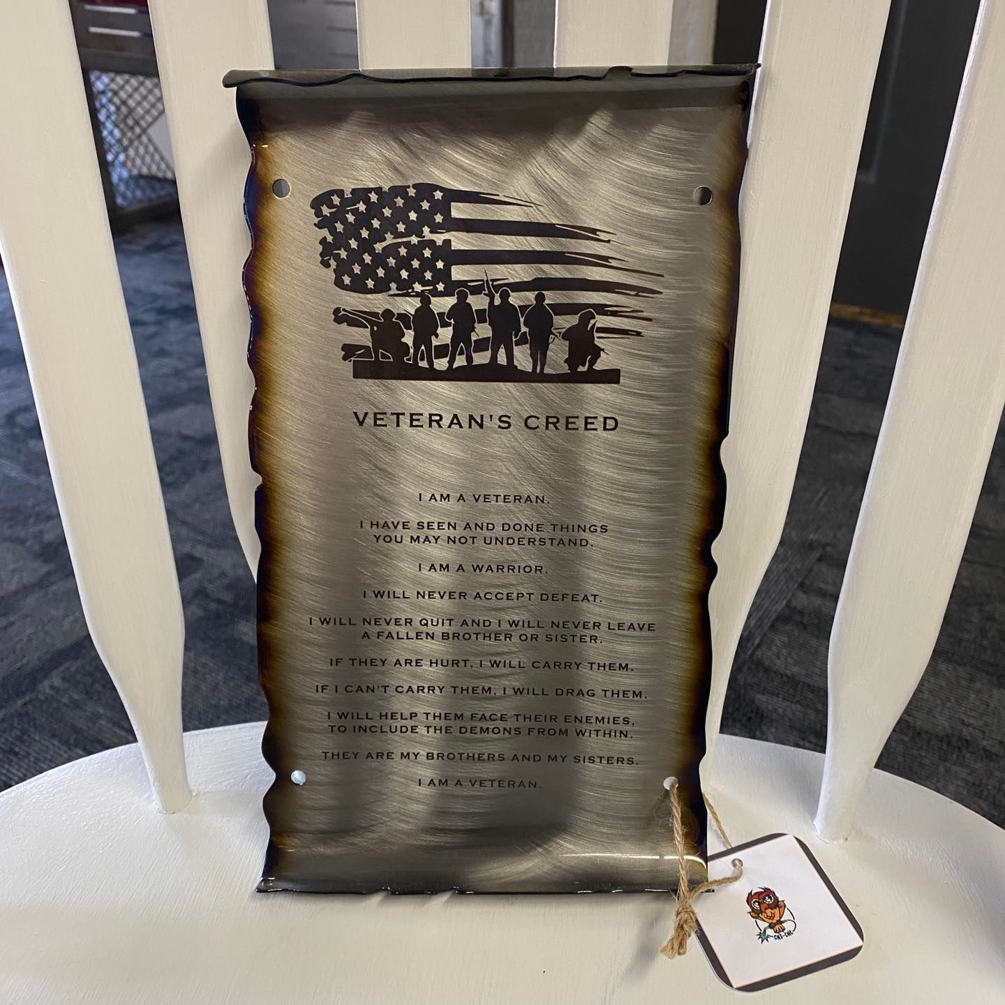 Metal art piece with an American flag, silhouettes of soldiers, and the 