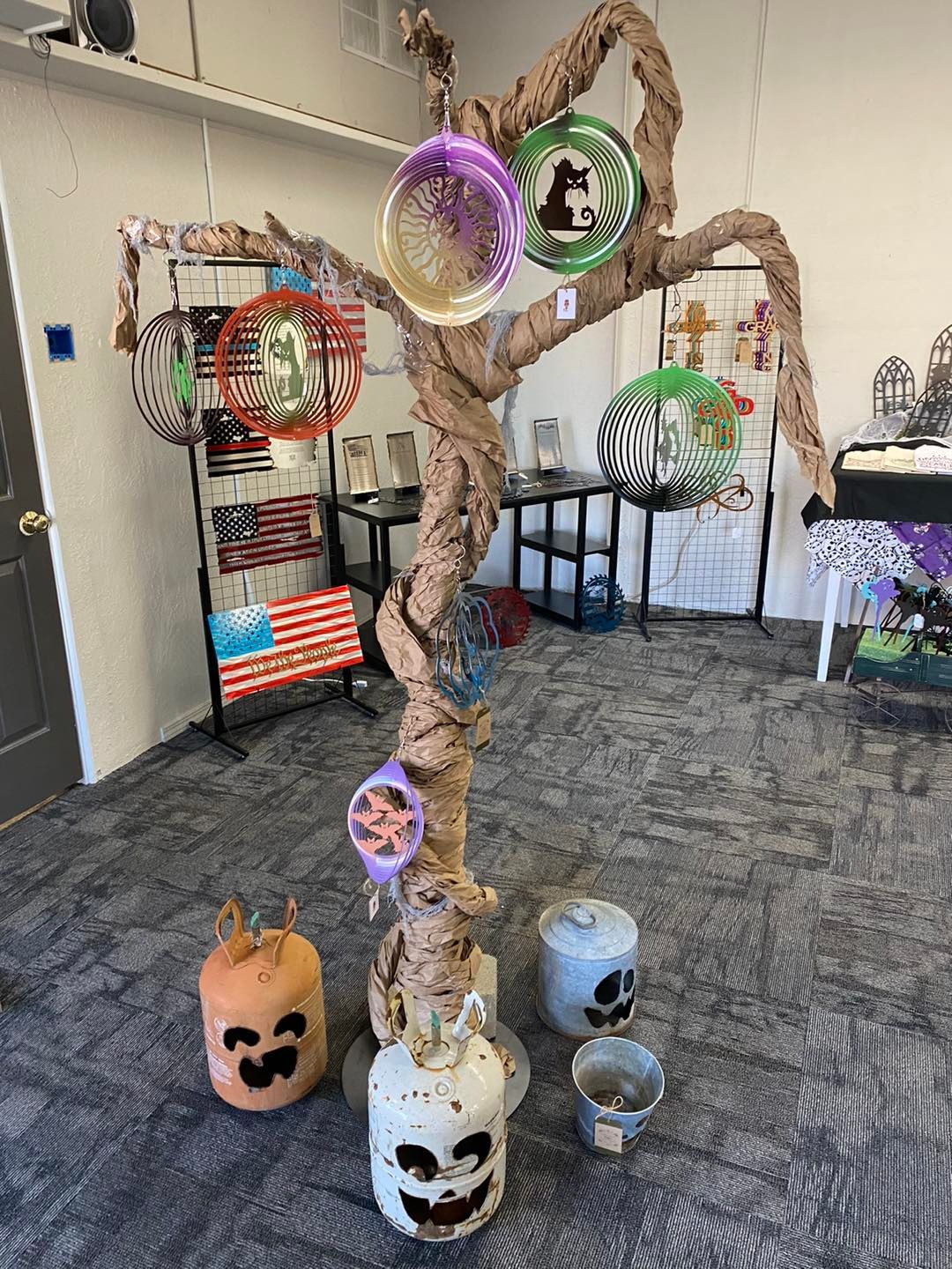 Display of decorative metal orbs and carved pumpkins in a shop; a twisted branch structure.