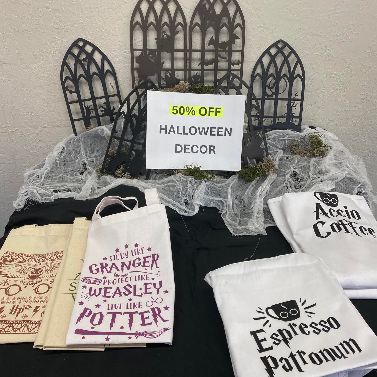 Halloween decor display with 50% off sign. Tote bags with Harry Potter-themed designs.