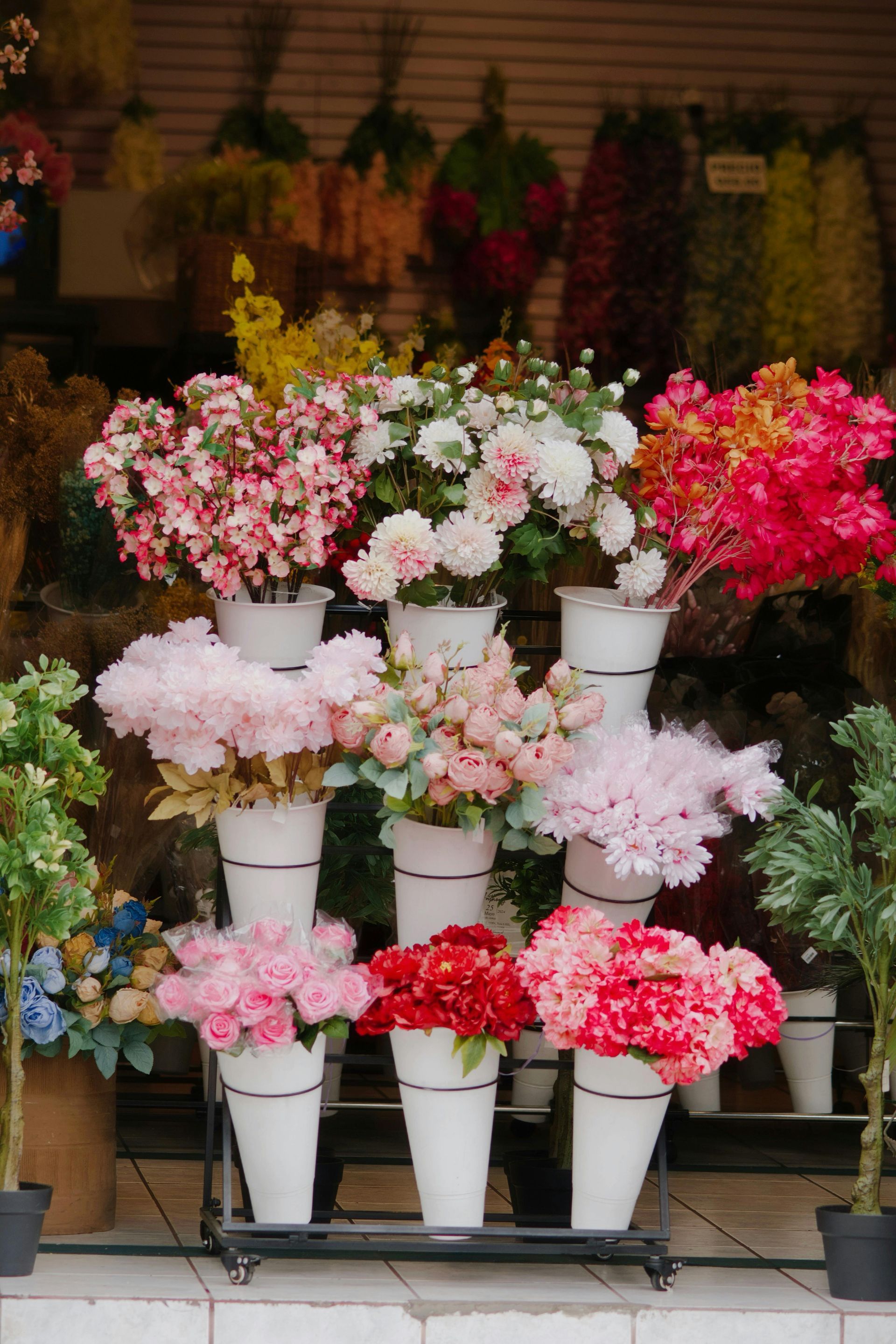 Colorful potted flowers arranged in tiers outside a shop