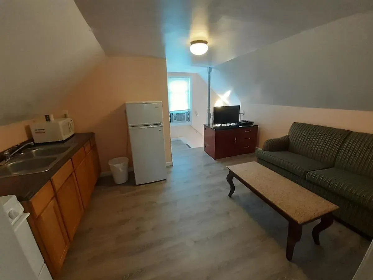 A living room with a couch , coffee table , refrigerator , microwave and television.