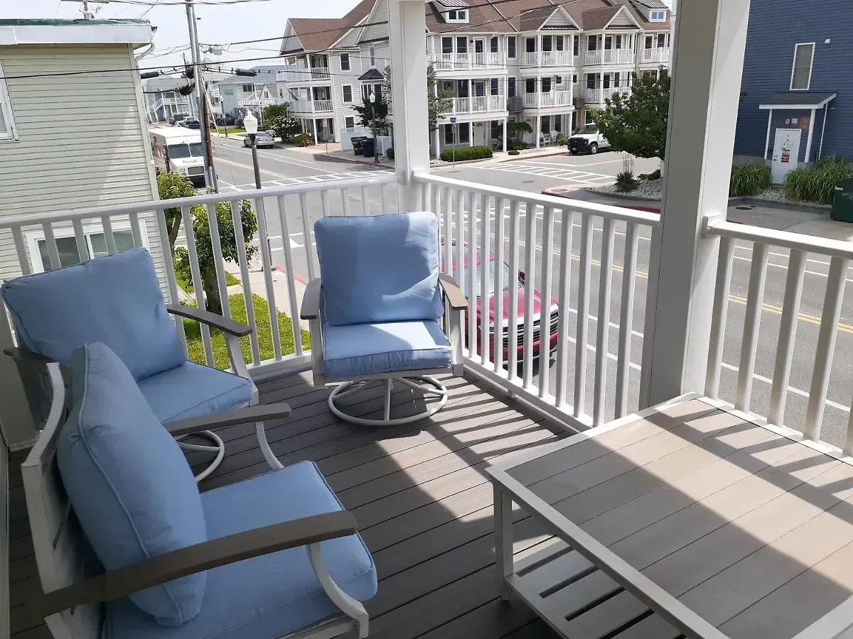 A balcony with blue chairs and a table with a view of the street