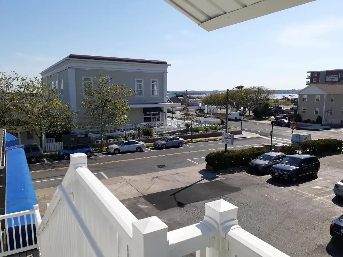 A view of a city street from a balcony with cars parked on the side of the road.