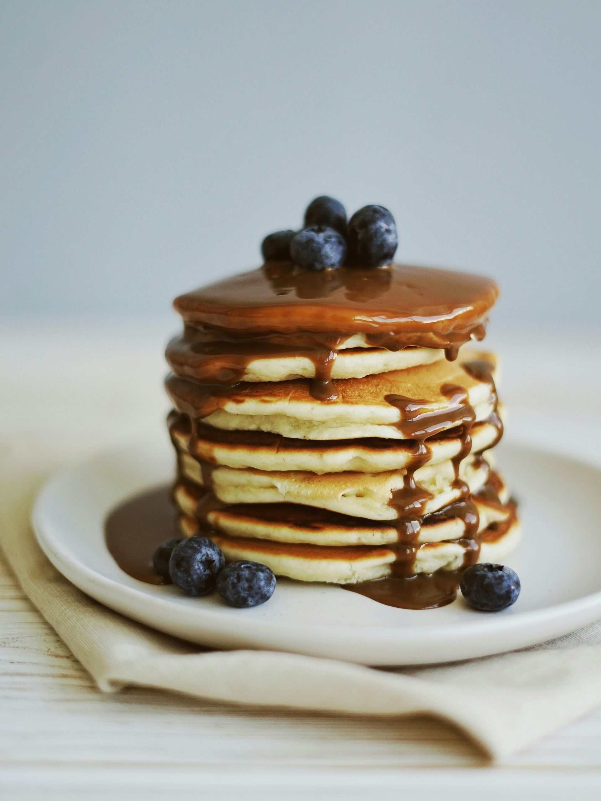 A stack of pancakes with chocolate sauce and blueberries on top