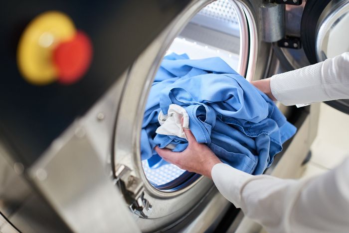 a person is putting a blue shirt in a washing machine .