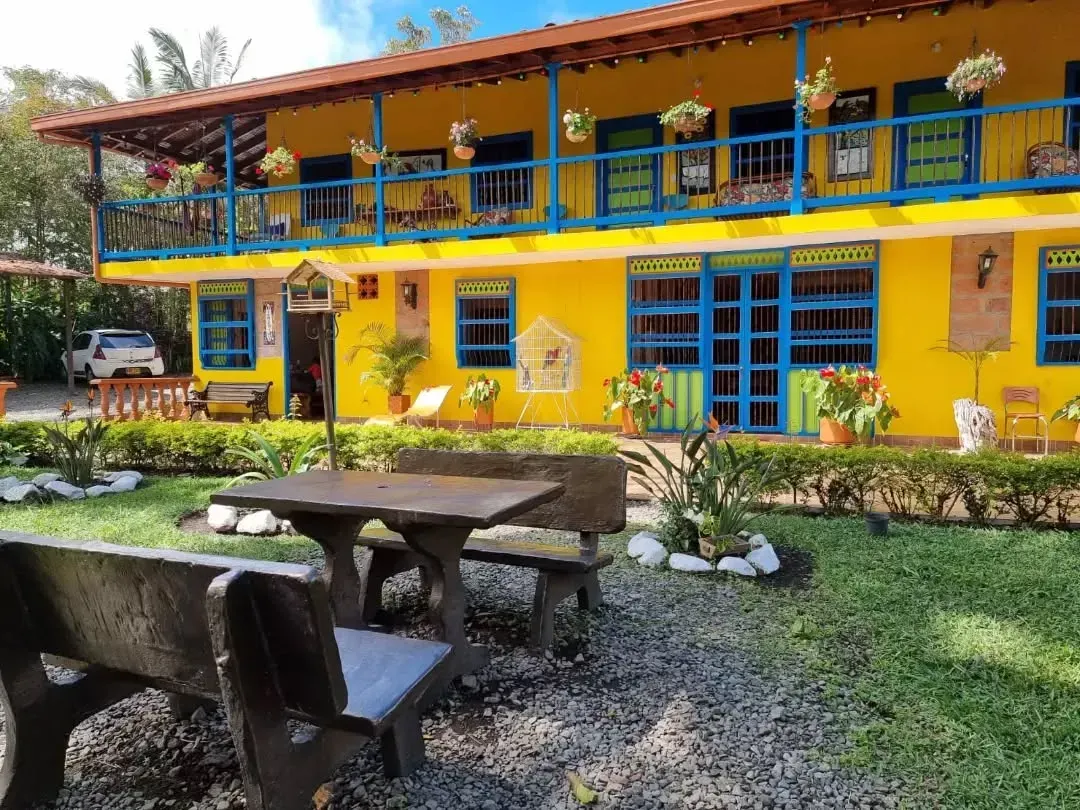 A yellow building with blue balconies and tables and chairs in front of it
