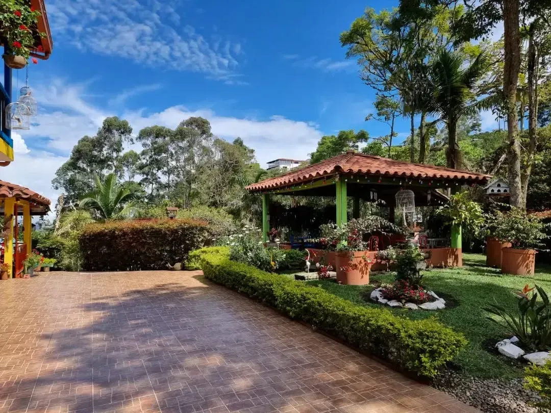 There is a gazebo in the middle of a garden surrounded by trees.