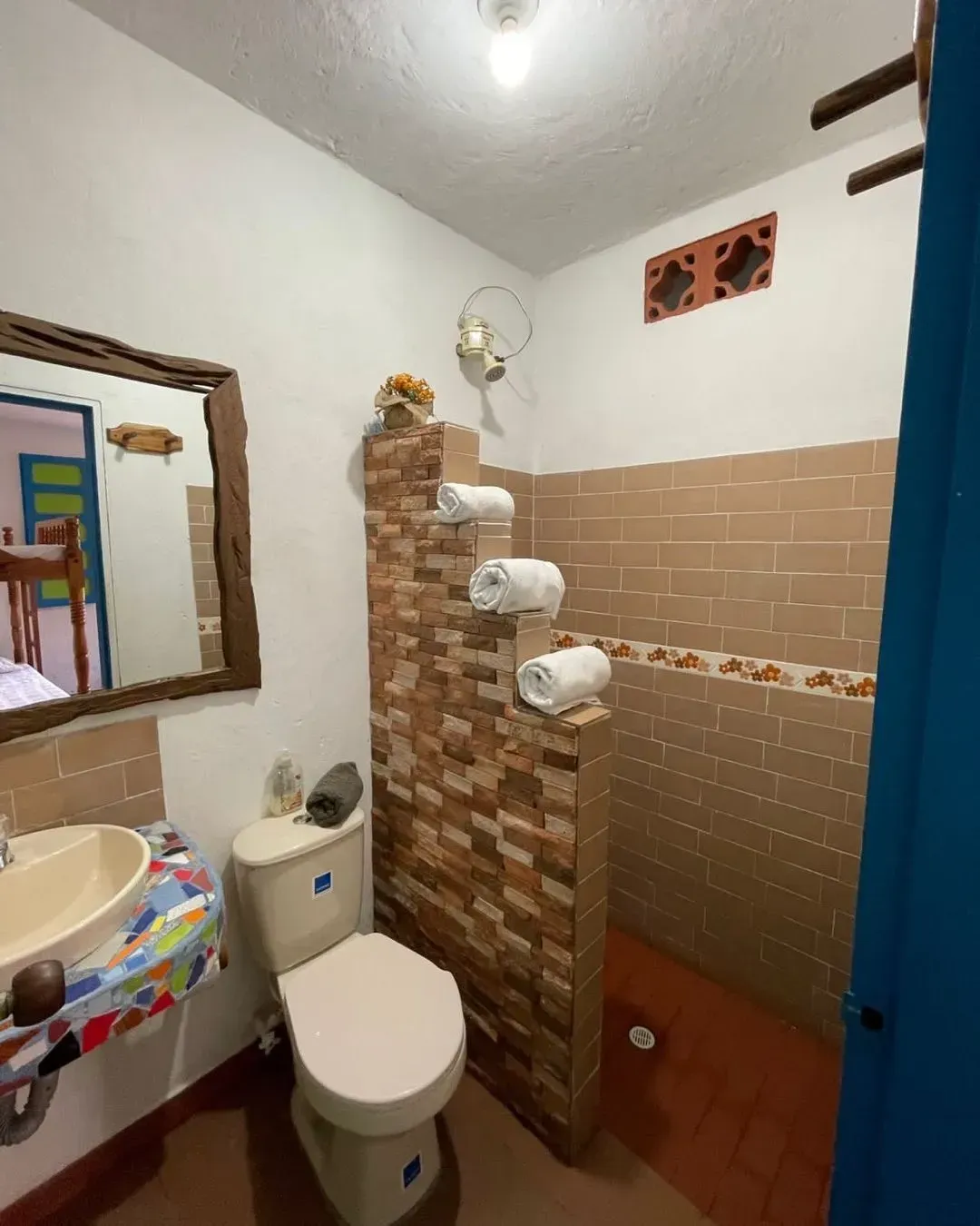 A bathroom with a toilet , sink , mirror and shower.