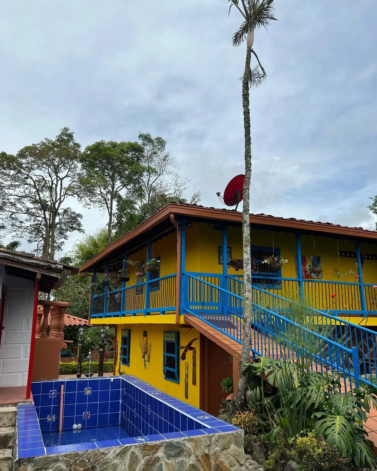 A yellow and blue house with a pool in front of it.