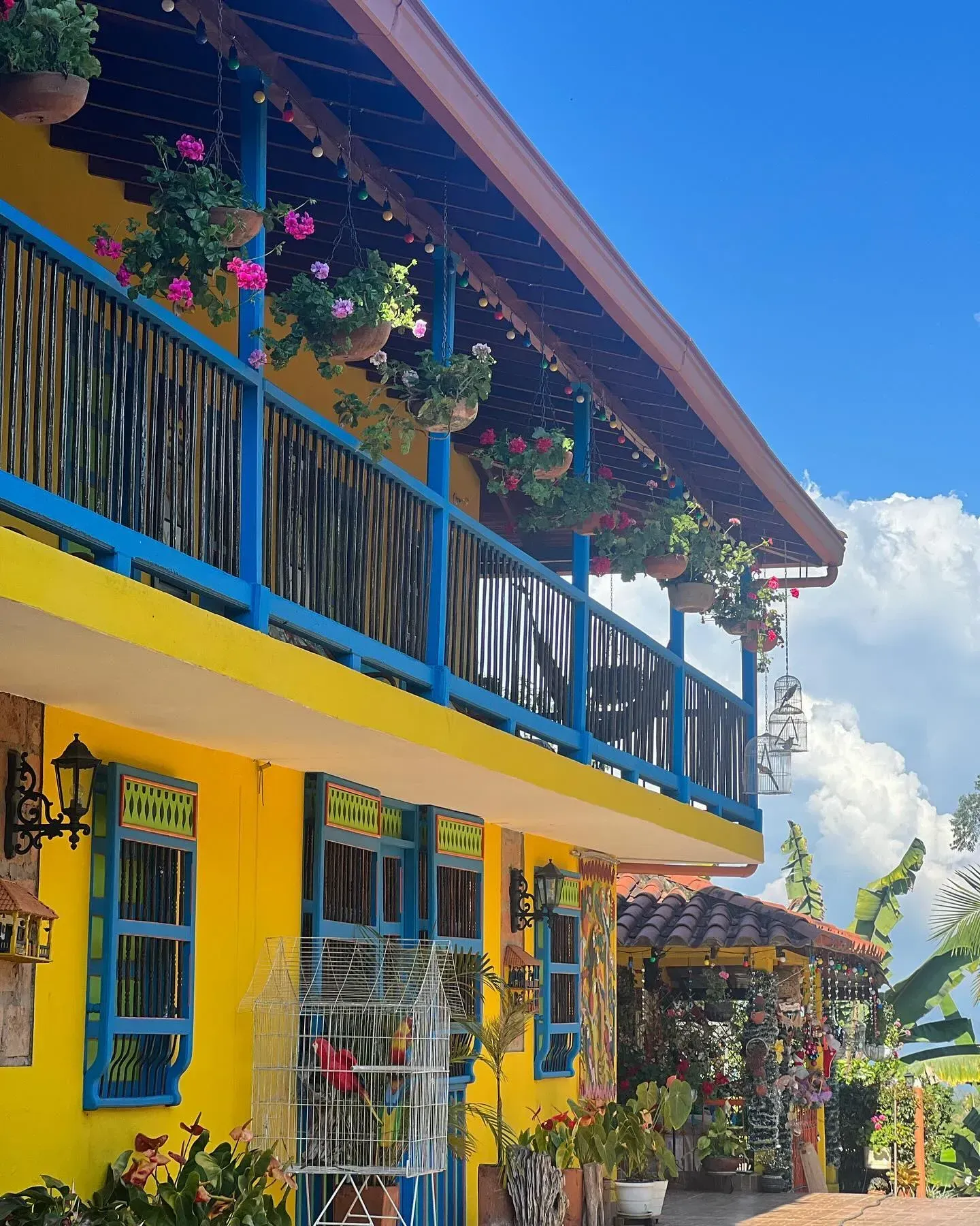 A yellow and blue building with flowers on the balcony