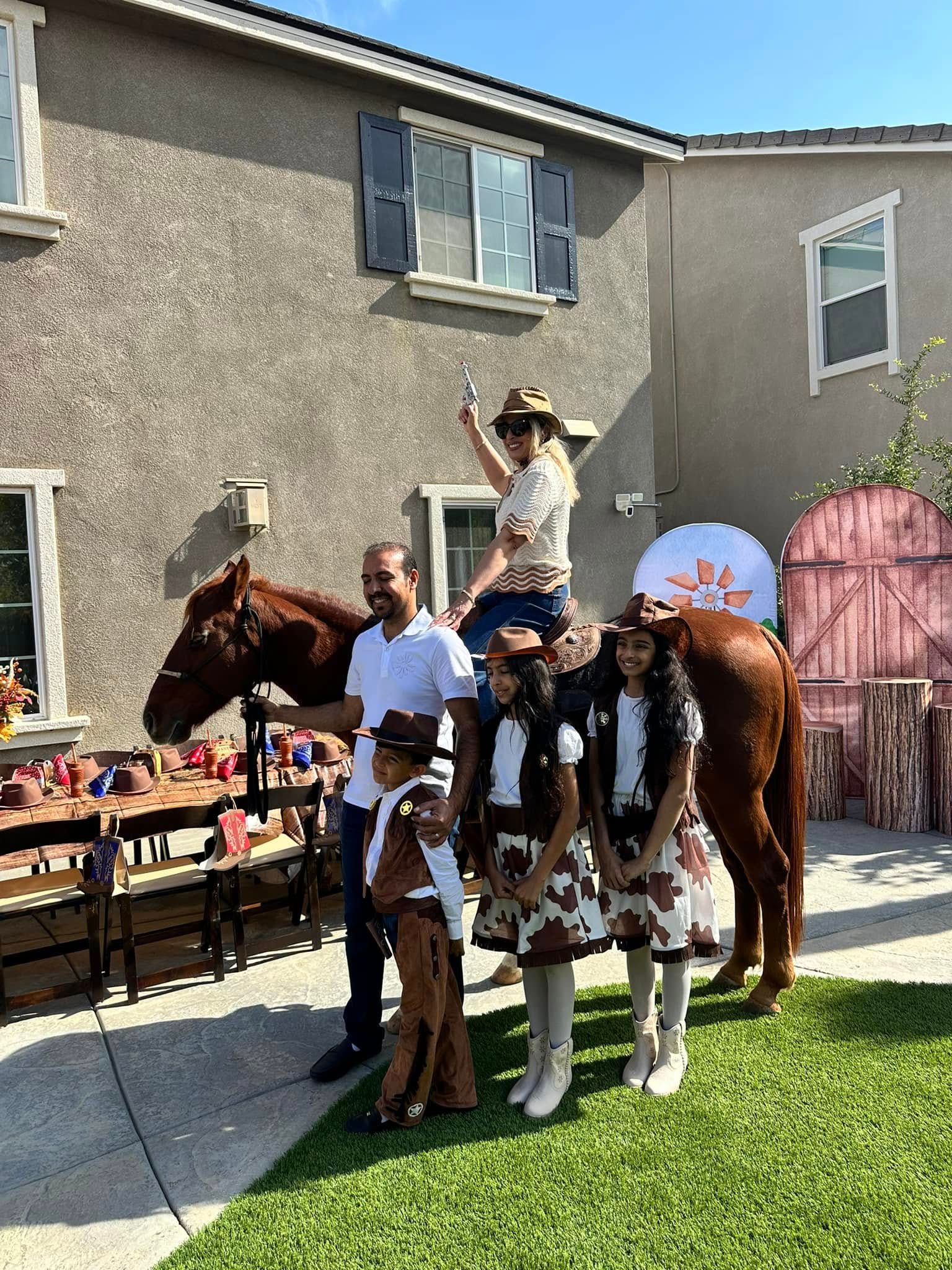 A group of people standing next to a horse in front of a house.