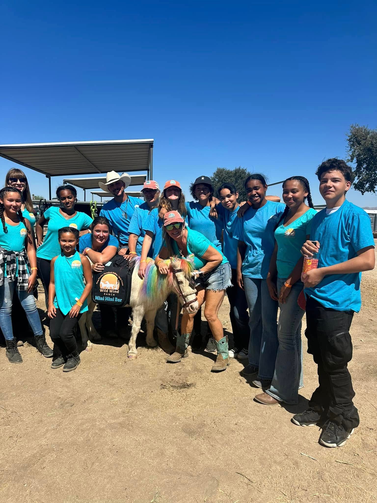 A group of people are posing for a picture with a pony.