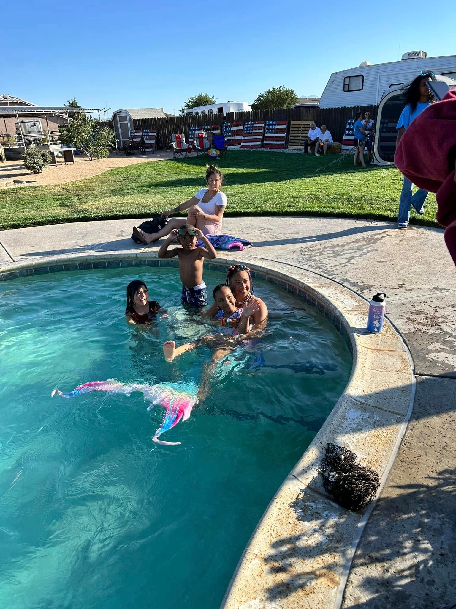 A group of people are swimming in a pool with a mermaid tail.