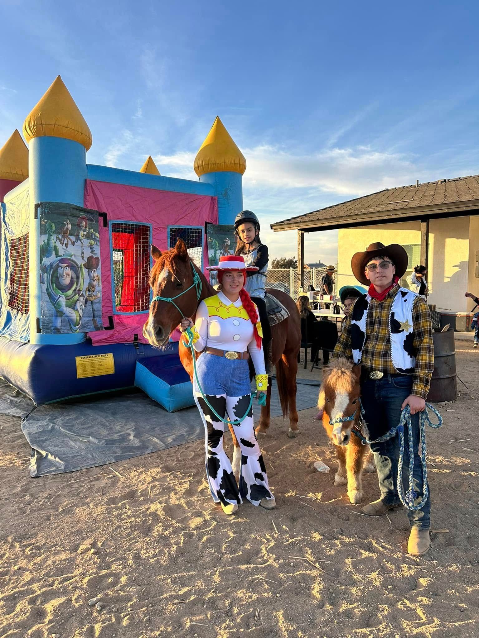 A group of people dressed as cowboys and cowgirls are standing next to a bouncy house.