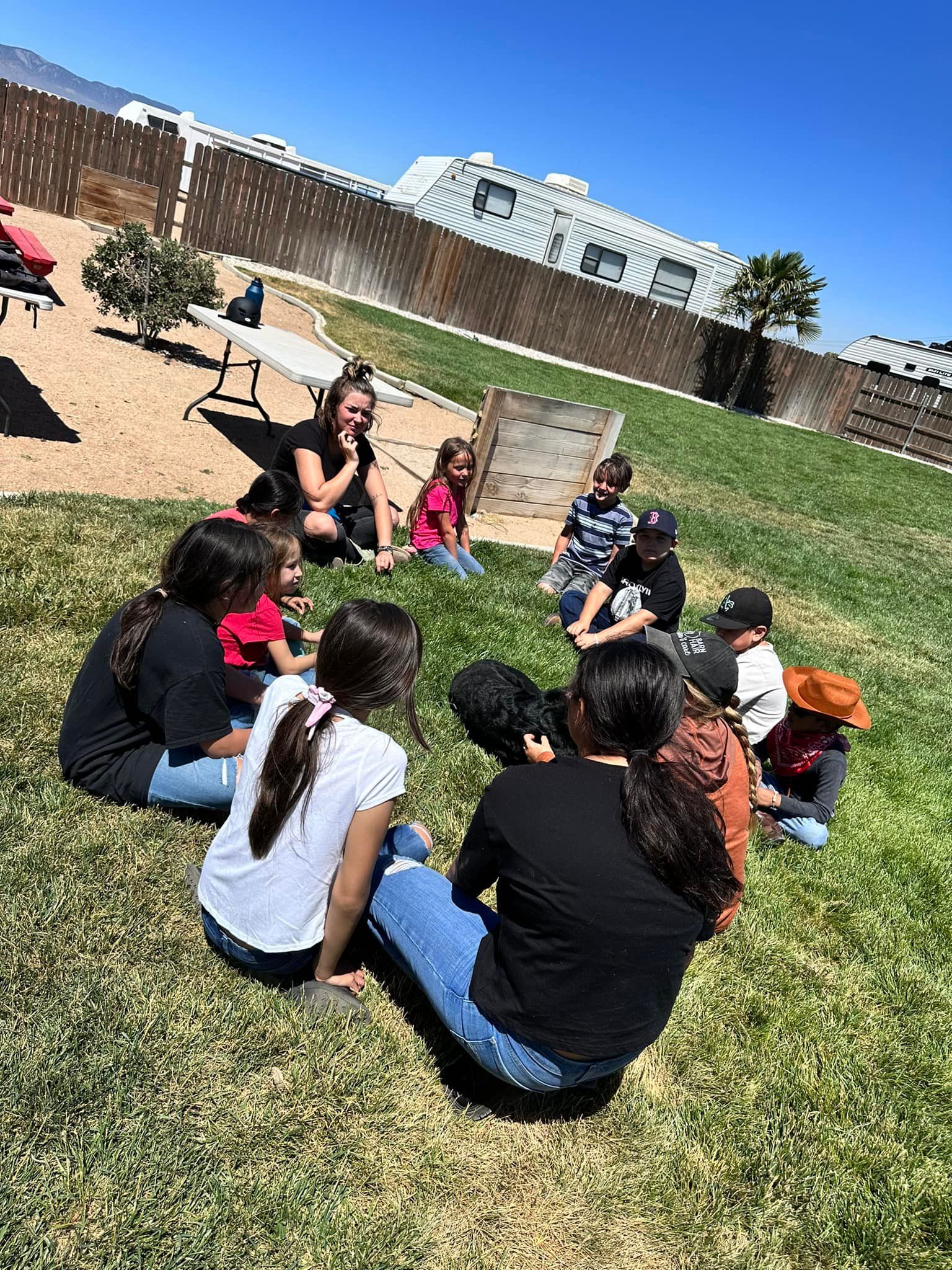 A group of people are sitting in a circle on the grass.