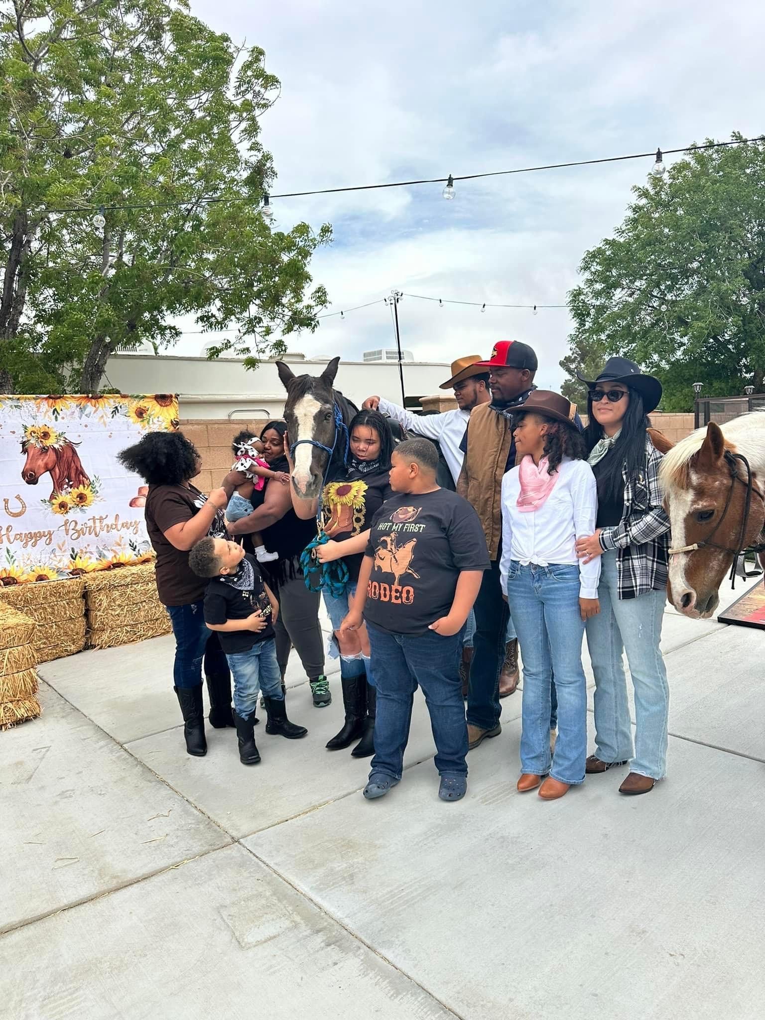 A group of people standing next to horses on a sidewalk.