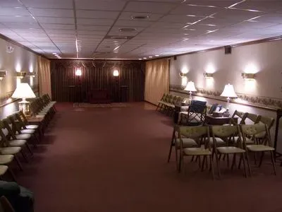 A large room with rows of folding chairs and lamps.