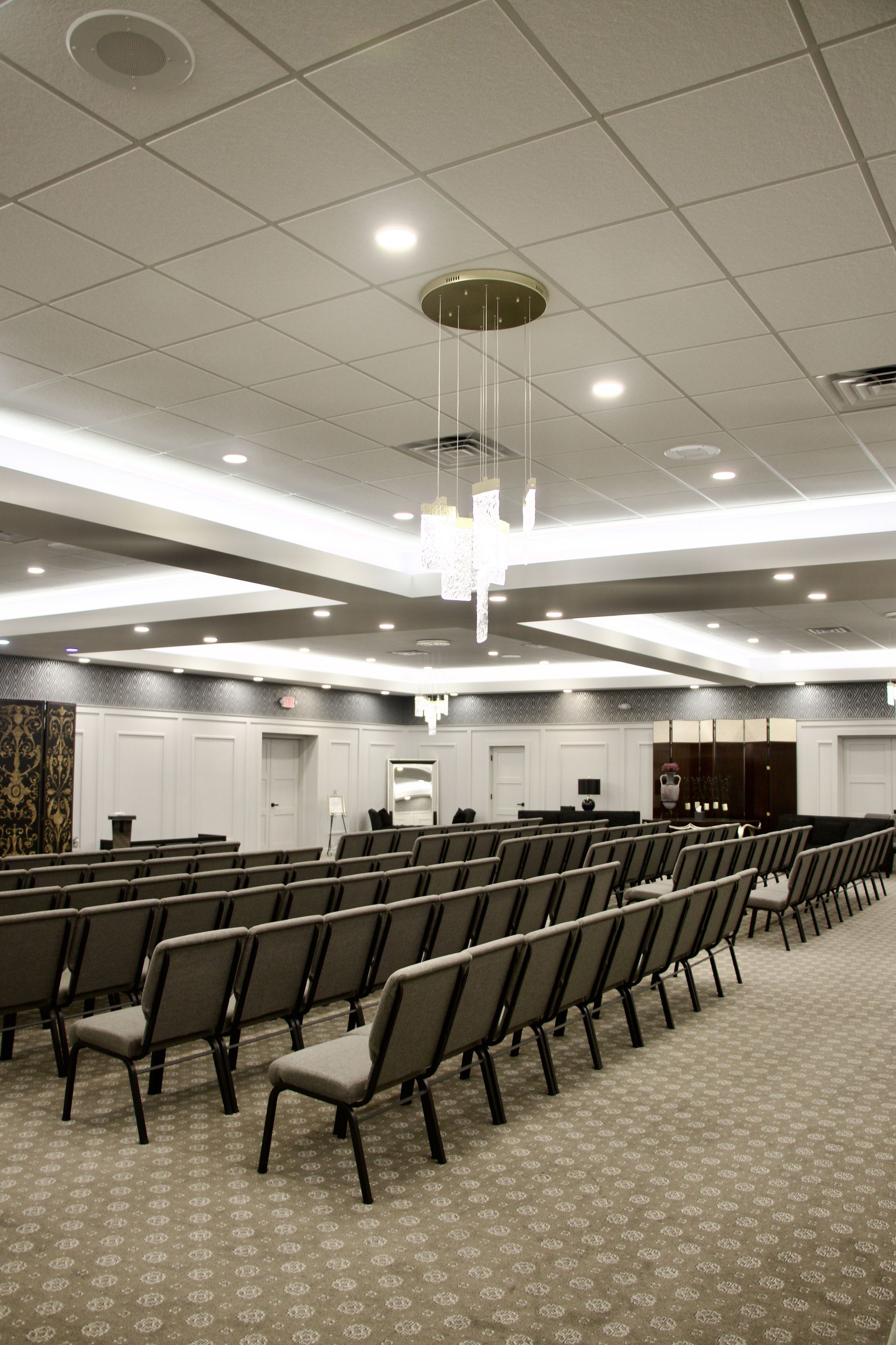 A large auditorium with rows of chairs and a chandelier hanging from the ceiling.