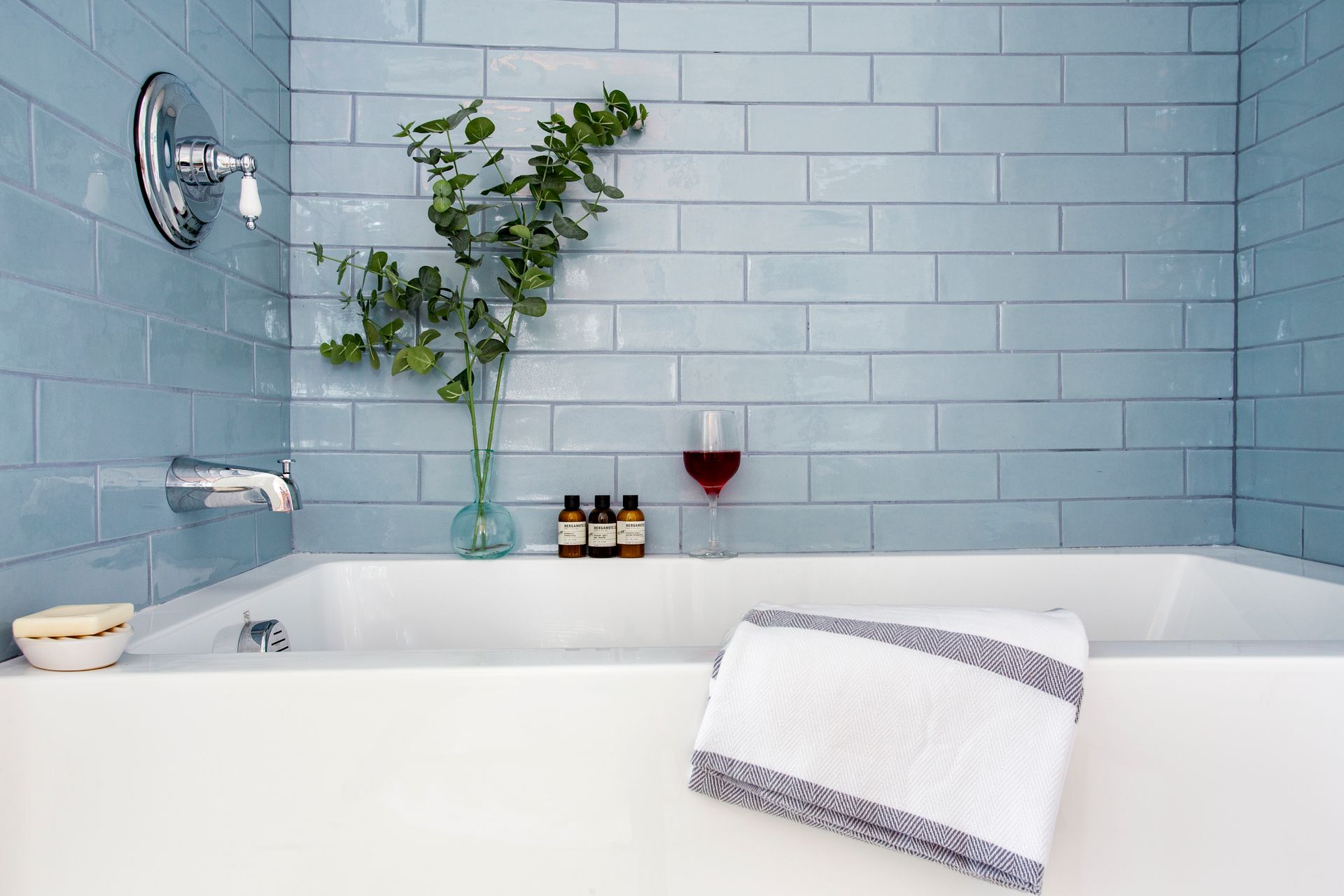 A bathtub with a towel and a glass of wine in it.