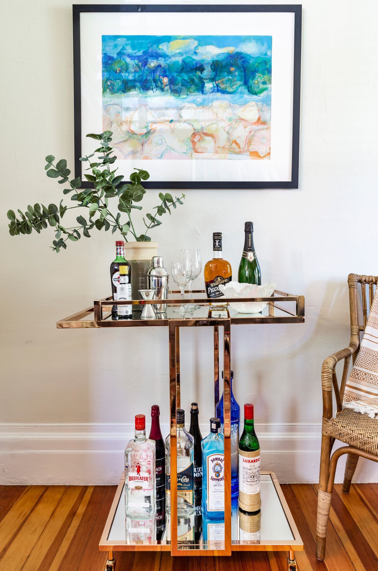 A bar cart with bottles of liquor on it in a living room.