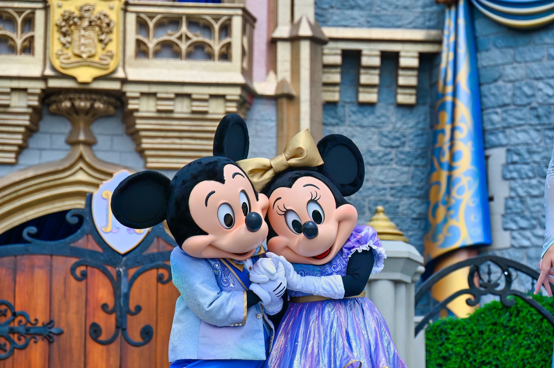 Mickey mouse and minnie mouse are hugging each other in front of a castle.