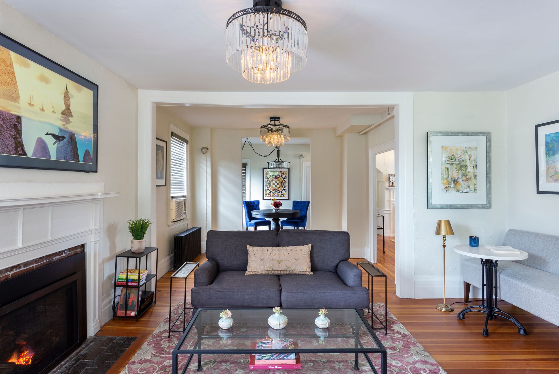 A living room with a couch , coffee table , fireplace and chandelier.