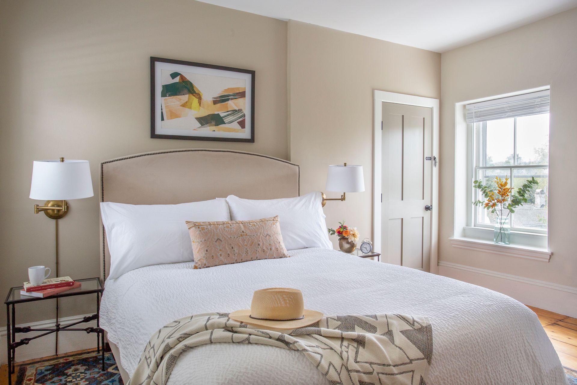 A bedroom with a bed , chairs , dresser , nightstand , and mirrors.