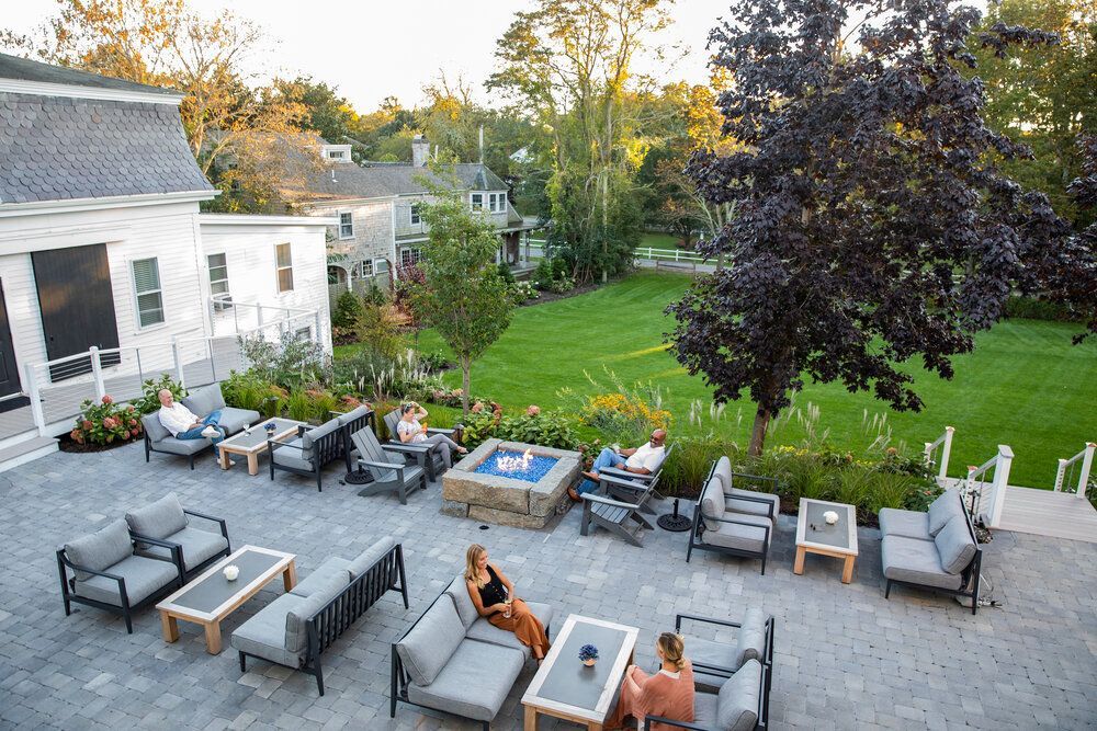 A group of people are sitting on a patio with a fire pit.