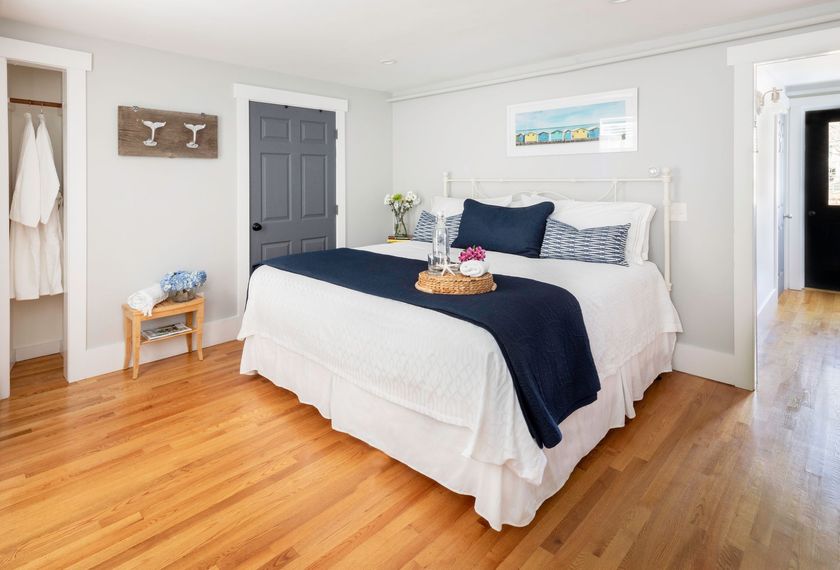 A bedroom with a king size bed and hardwood floors.