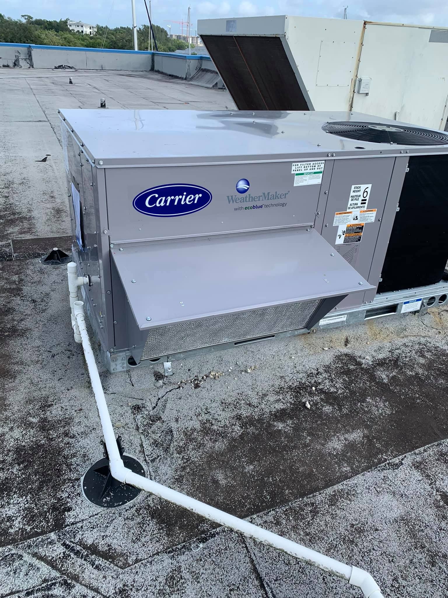 A carrier air conditioner is sitting on top of a roof.