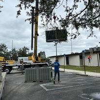 A crane is lifting a large box from a truck in a parking lot.