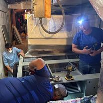 A group of men are working on a machine in a room.