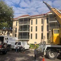 A crane is parked in front of a large building.