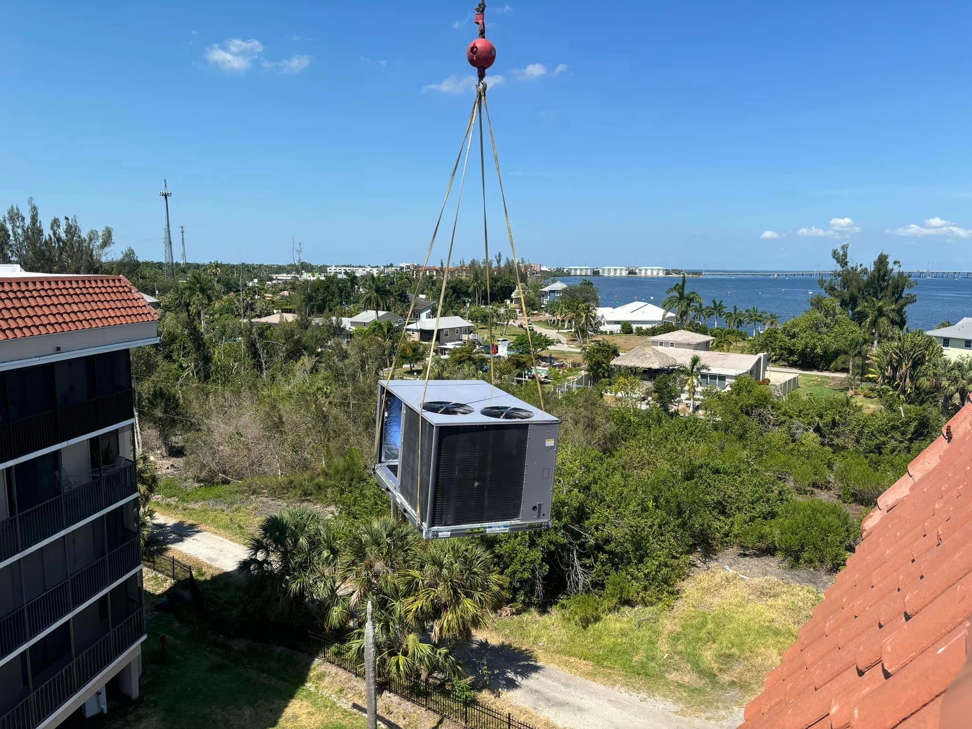 A large air conditioner is being lifted by a crane.