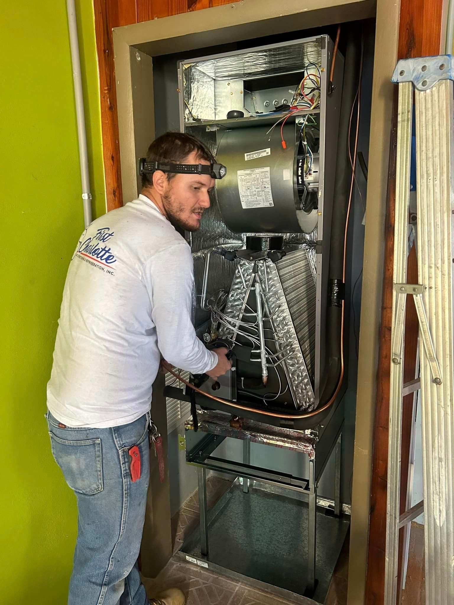 A man is working on an air conditioner in a room.