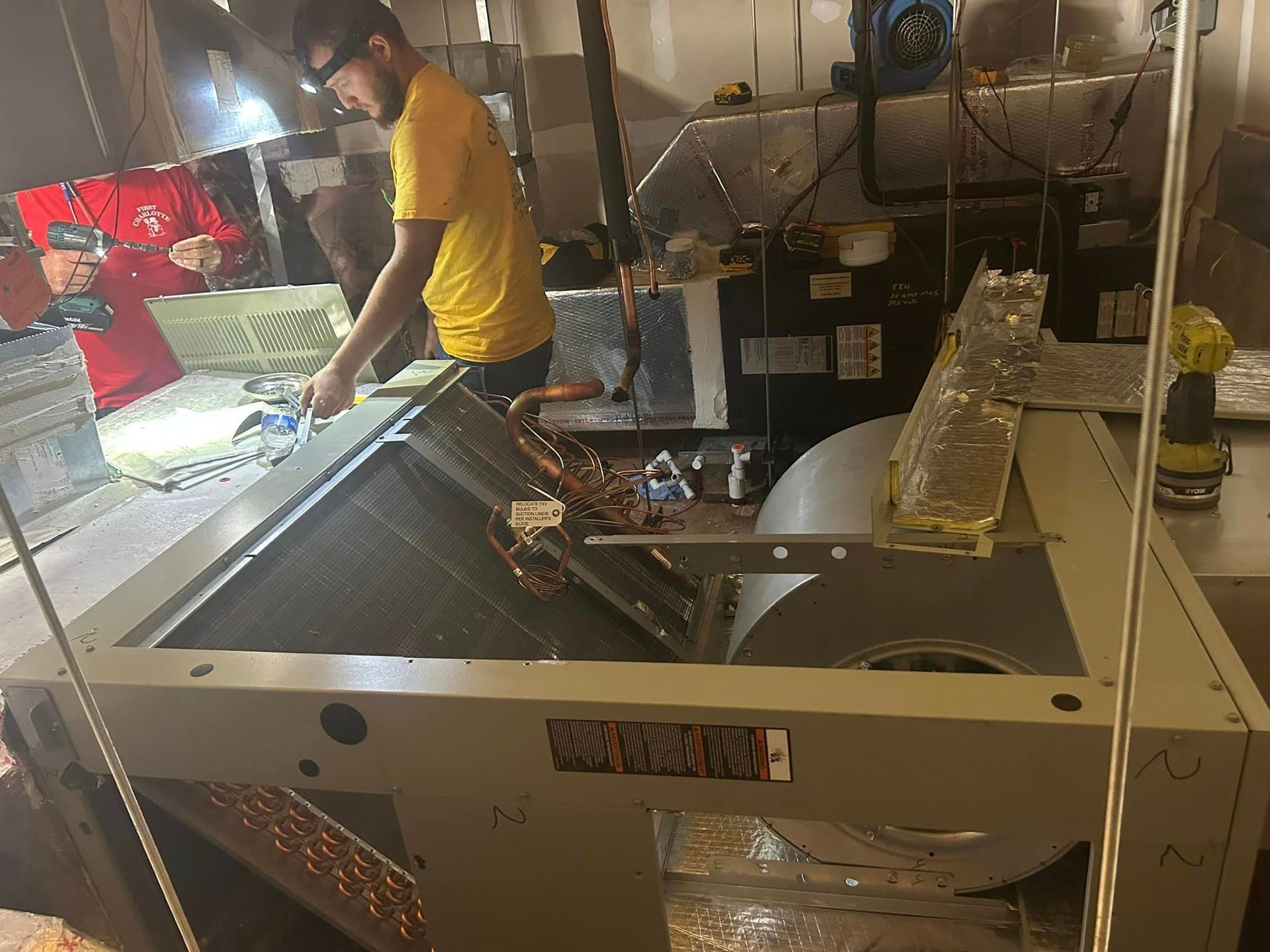 A man in a yellow shirt is working on a machine in a kitchen.