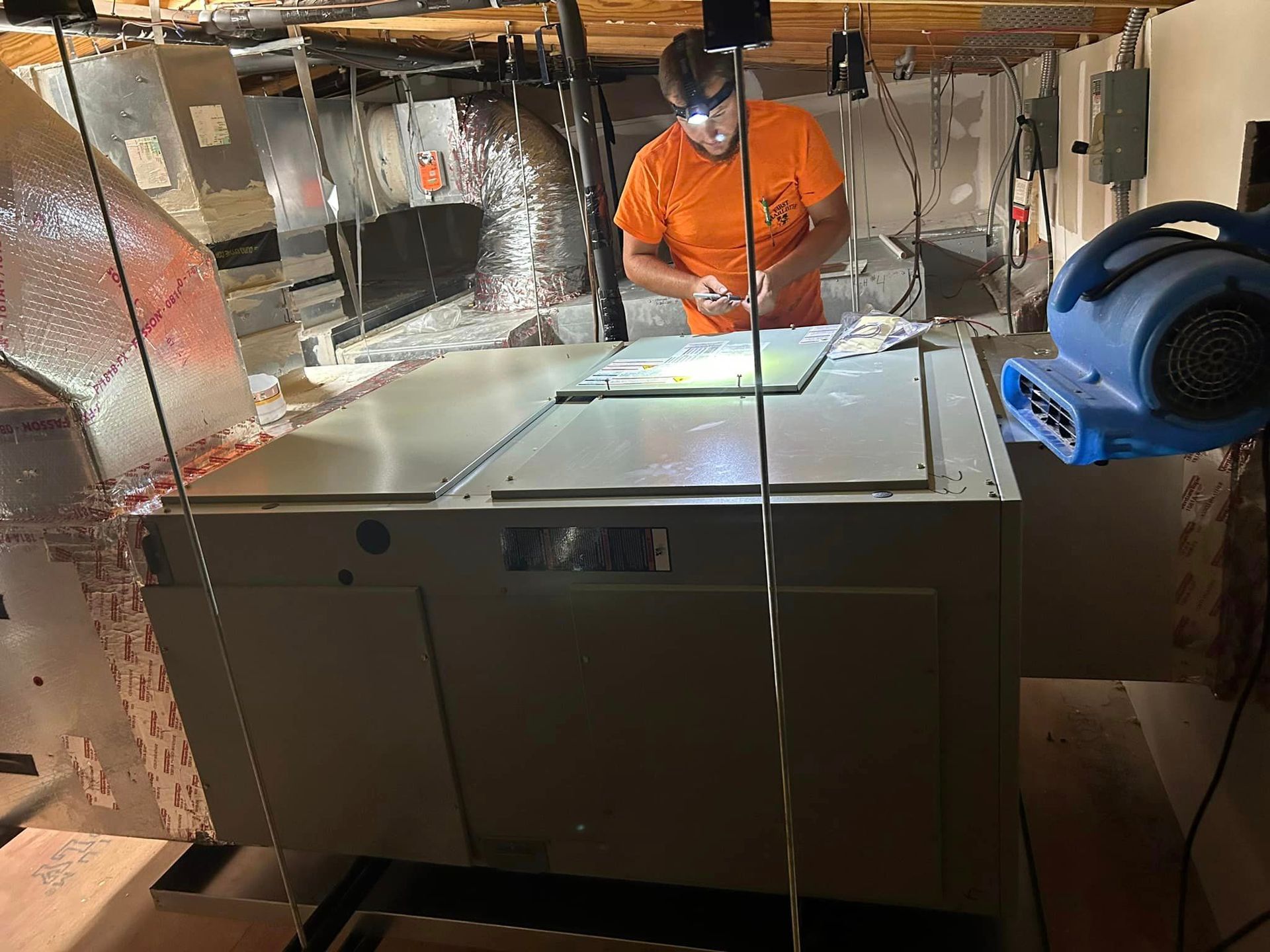 A man is working on an air conditioner in a basement.