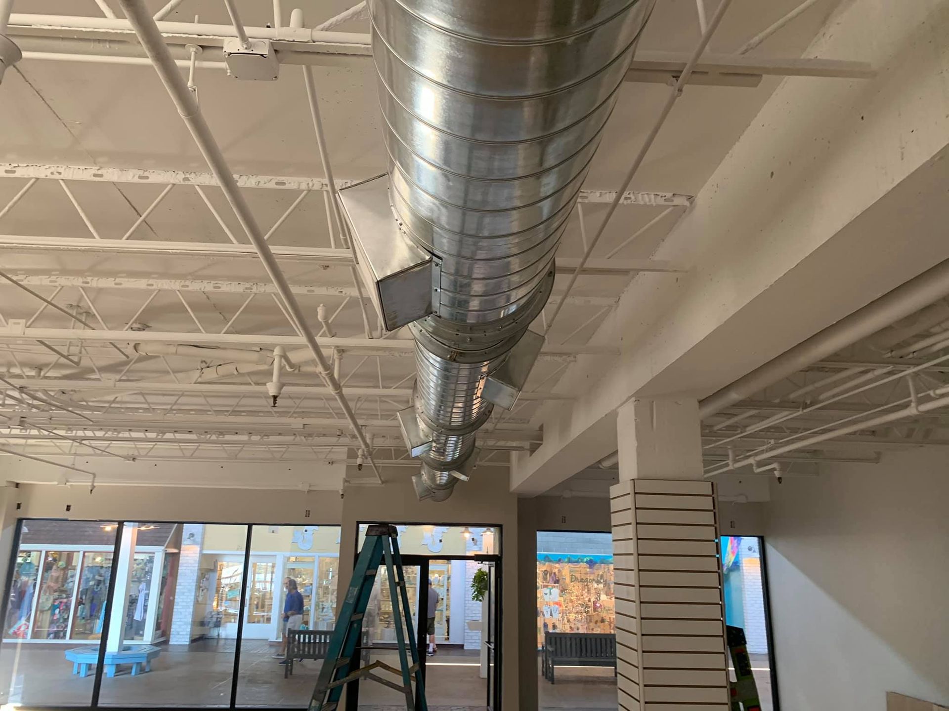 A large metal pipe is hanging from the ceiling of a building.