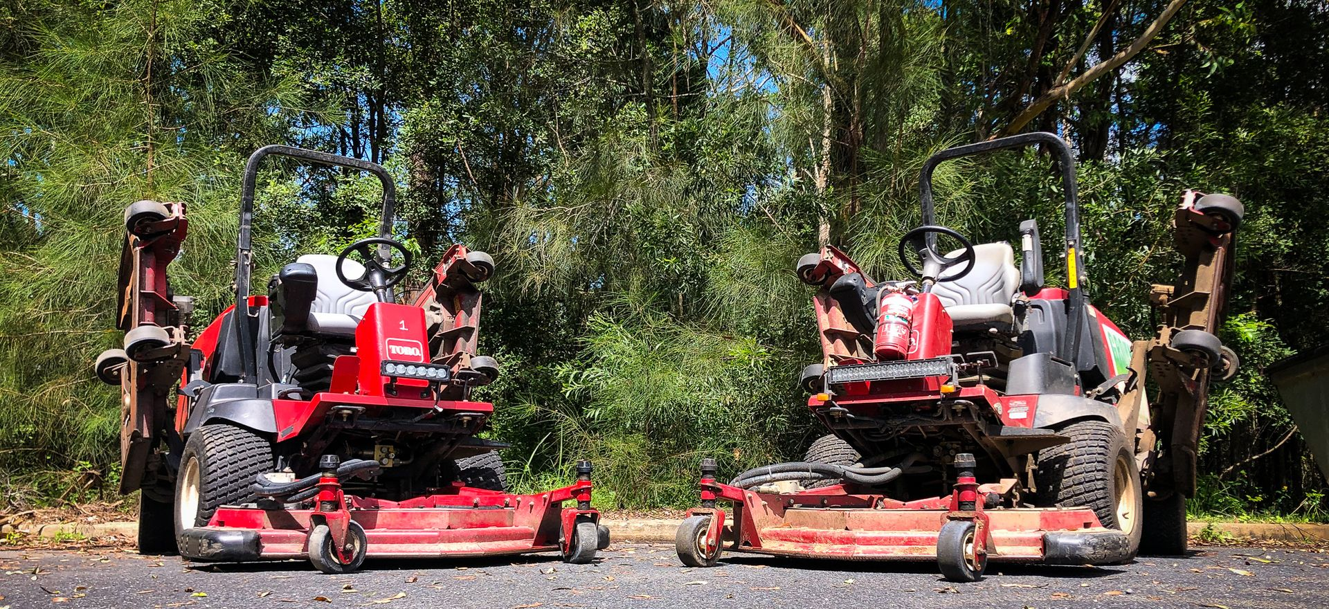 Two Red Riding Lawn Mowers Parked Side by Side on A Wooded Path — Ground Control Property Maintenance In North Boambee Valley, NSW