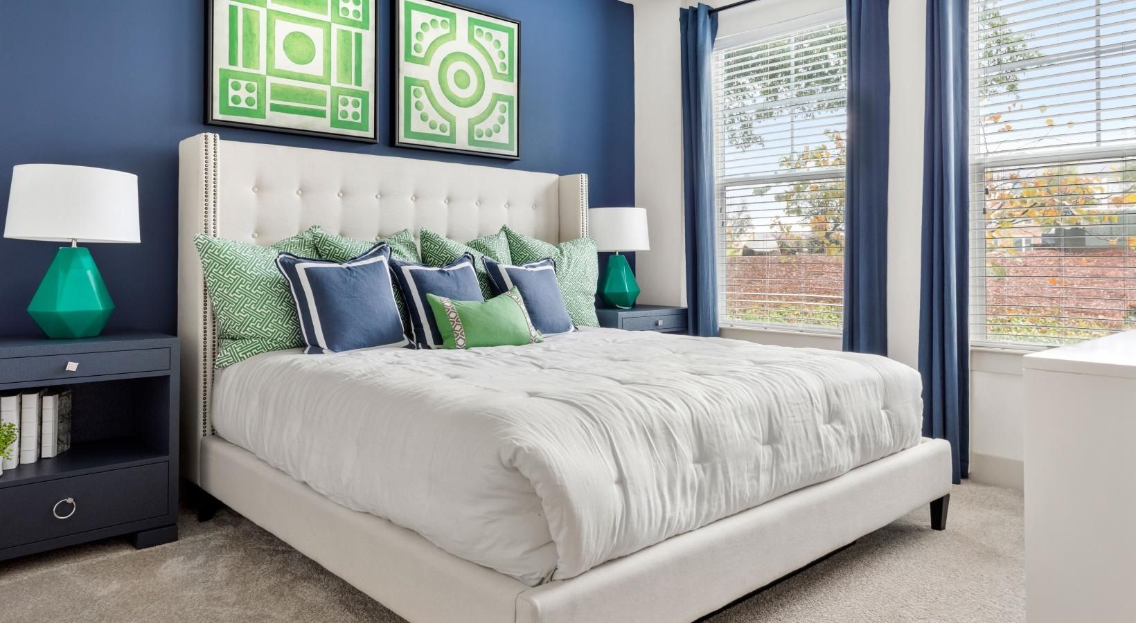 A bedroom with a bed , lamps , nightstands and blue walls.