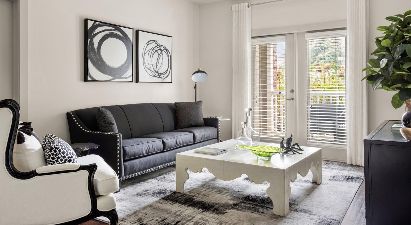 A living room with a black couch and a white coffee table.