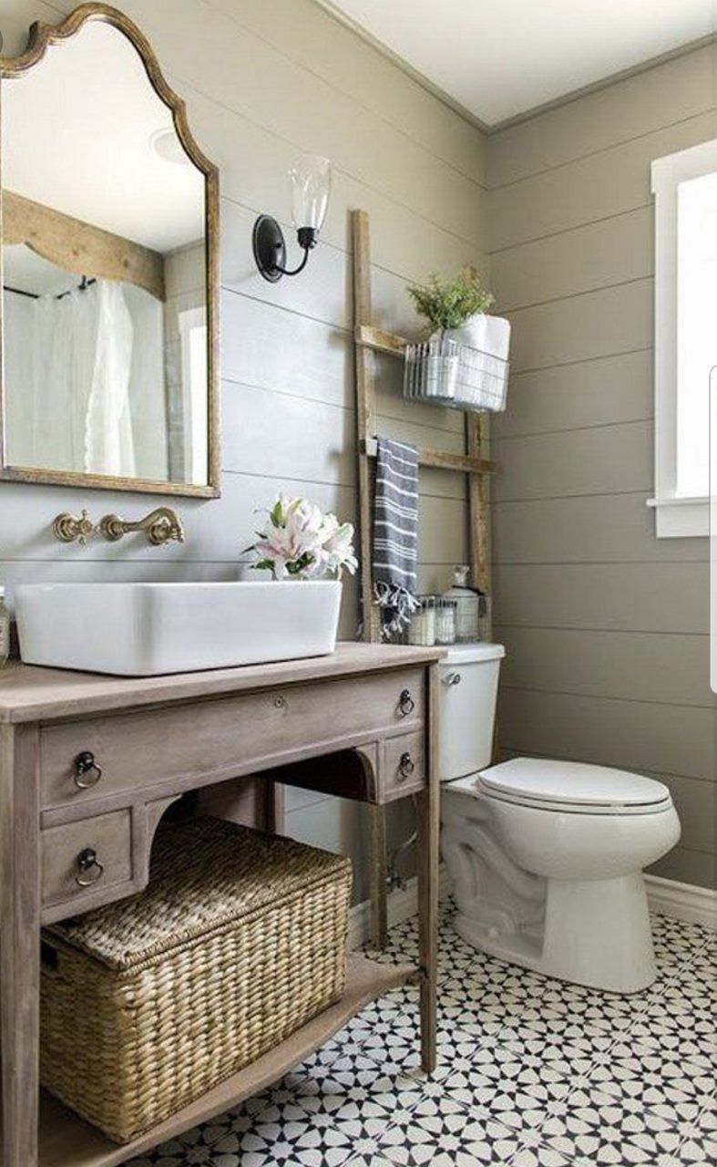 Small bathroom with white toilet, pedestal sink, patterned floor tile, wicker basket, and wall mirror.