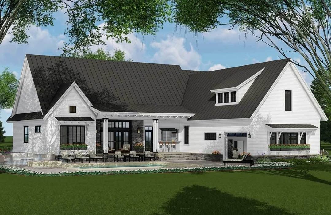 Modern white house with black roof, large windows, and landscaped front lawn under a blue sky