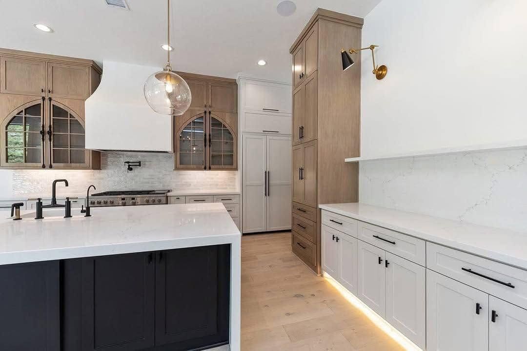 Modern white kitchen with black island, wood accents, and built-in cabinetry