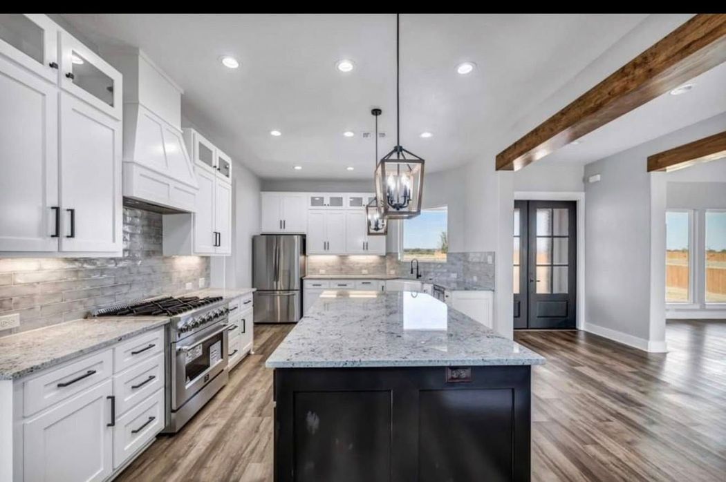 Bright modern kitchen with white cabinets, gray island, stainless appliances, and wood floors