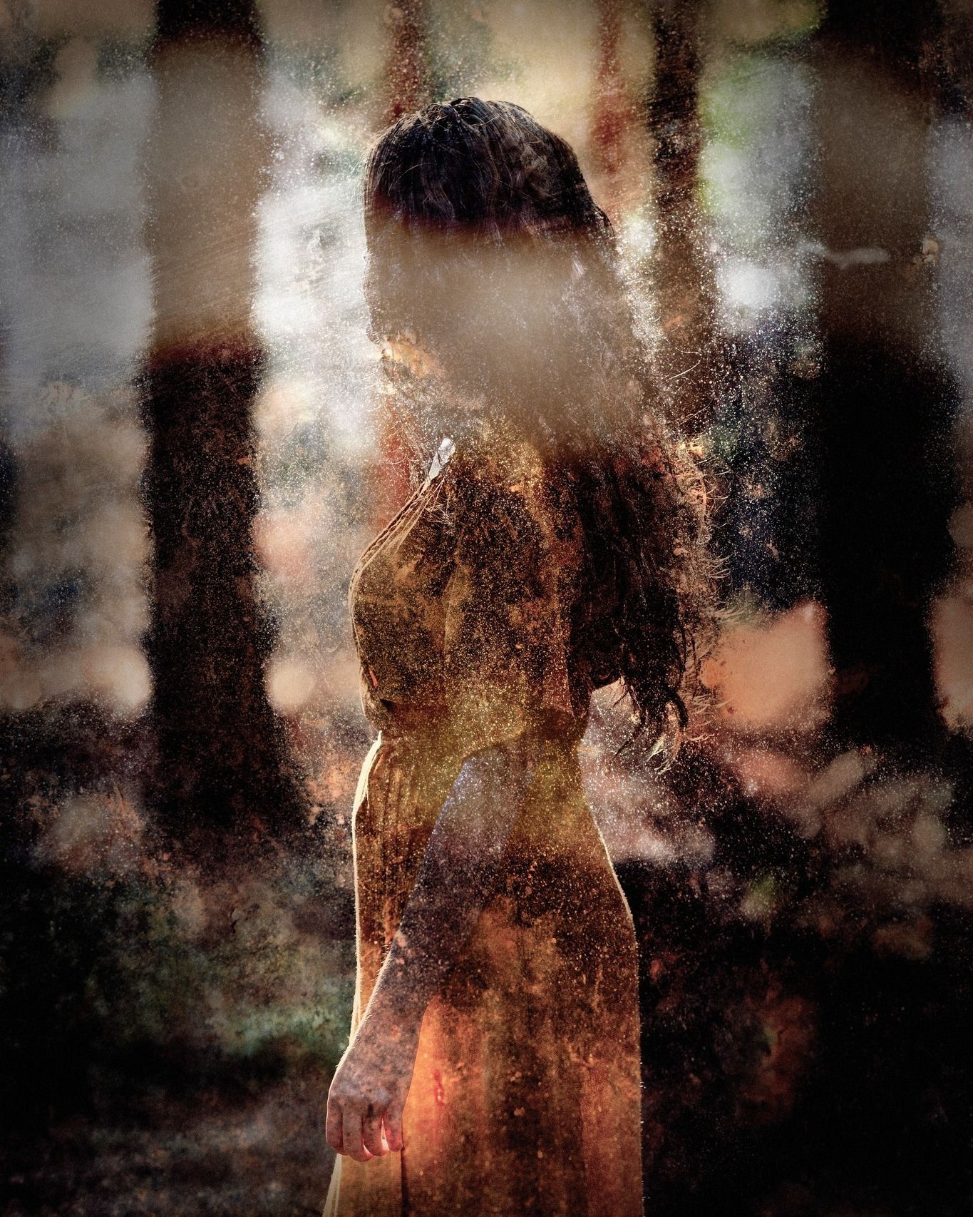 A woman in a long dress is standing in the woods.