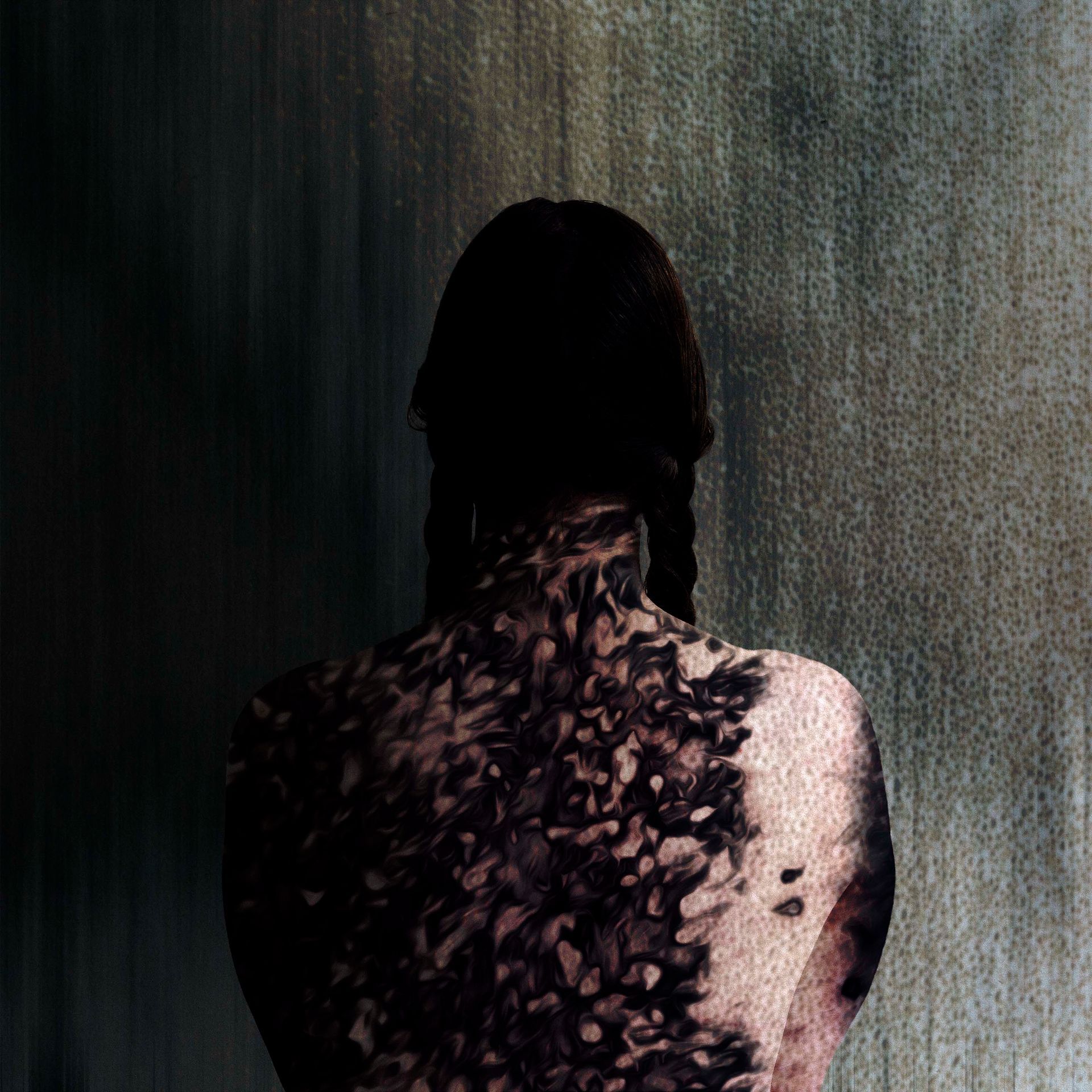 A woman with a tattoo on her back is standing in front of a wall.