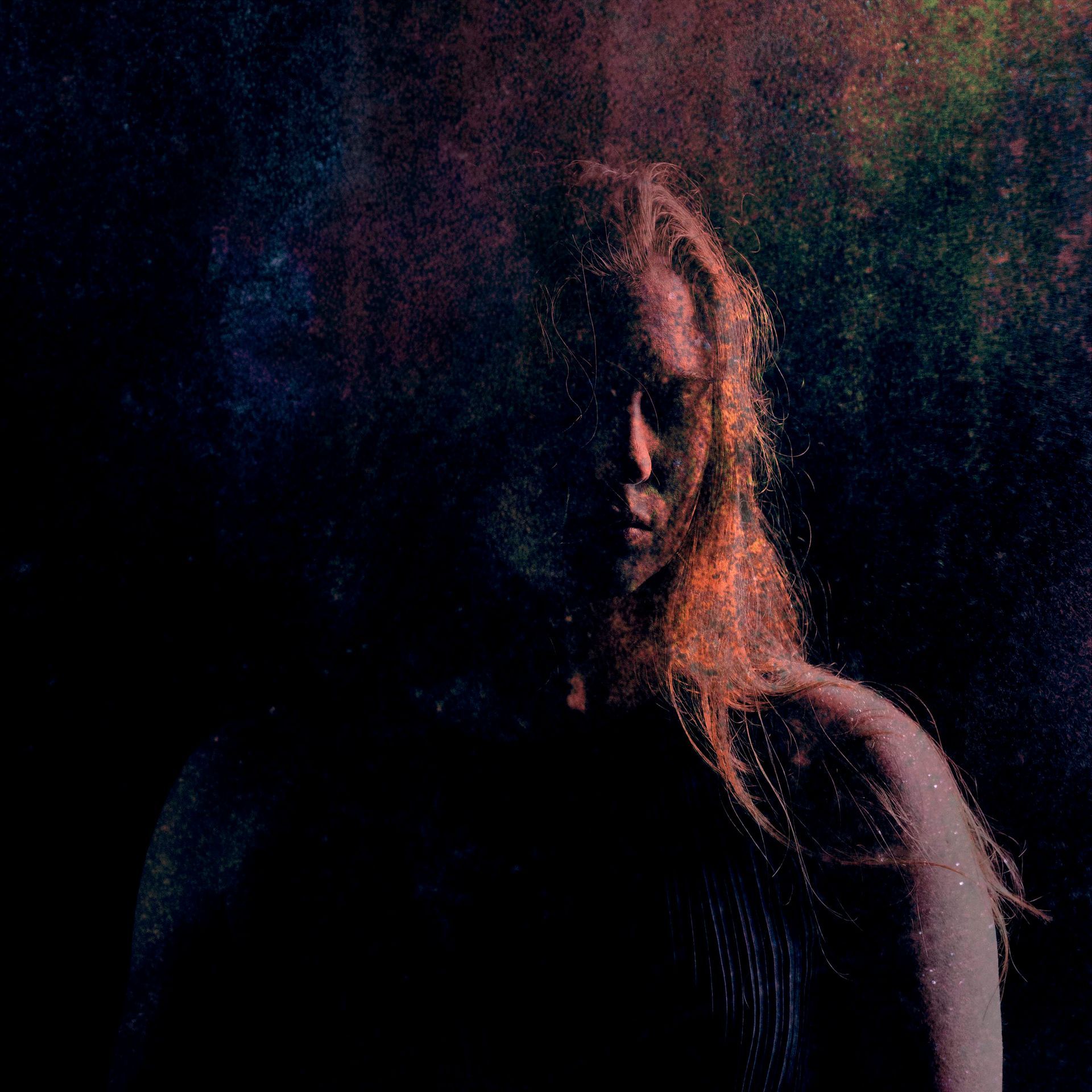 A woman with long hair is standing in the dark.